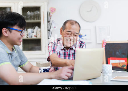 Son helping senior father using laptop in kitchen Stock Photo