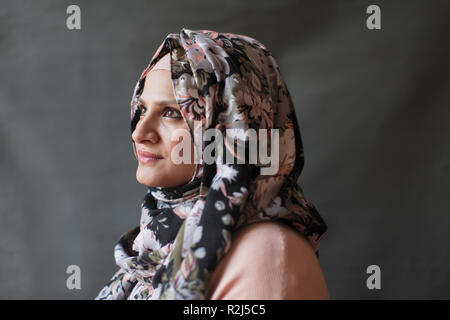 Serene, thoughtful woman wearing floral hijab, looking away Stock Photo