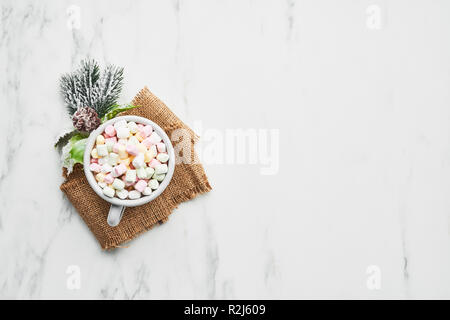 Cup of traditional Christmas hot chocolate or cocoa with marshmallow. Top view, white marble table, copy space. Stock Photo