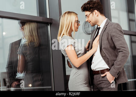 side view of businesspeople hugging and looking at each other in office, flirt and office romance concept Stock Photo
