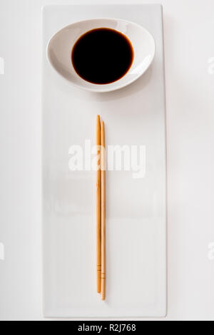 Top view of plate with soy sauce and chopsticks on white slate Stock Photo