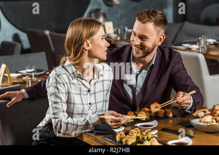 Attractive smiling couple amorously looking at each other while having dinner in restaurant Stock Photo