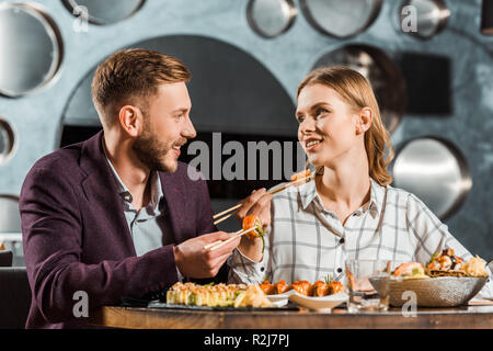 Happy young adult couple looking at each other while having dinner together in restaurant Stock Photo
