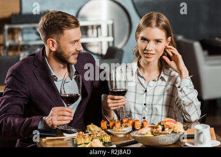 Beautiful young adult couple drinking wine and eating sushi in restaurant Stock Photo