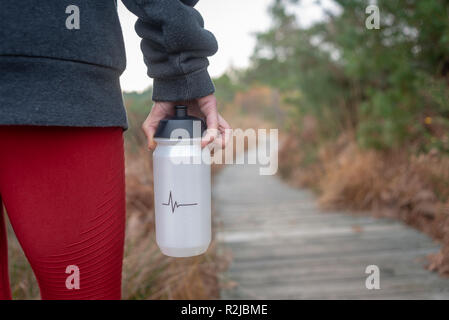 close up of a woman holding a plastic drinking bottle by her side while walking Stock Photo