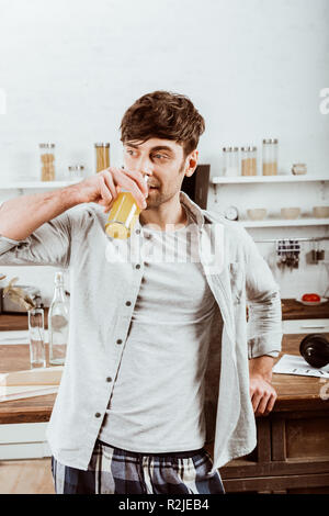 man drinking orange juice on breakfast in kitchen at home Stock Photo