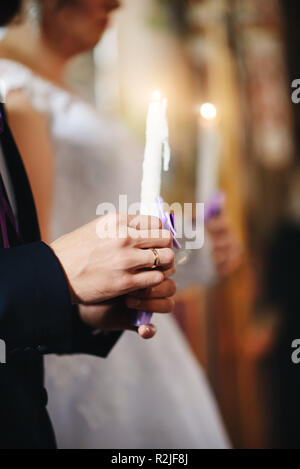 the hand of the bridegroom holding a burning candle at the wedding ceremony. Stock Photo