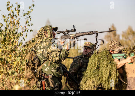 Sniper team armed with large caliber, sniper rifle, shooting enemy targets on range from shelter, sitting in ambush Stock Photo