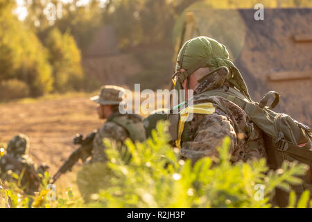 Sniper team armed with large caliber, sniper rifle, shooting enemy targets on range from shelter, sitting in ambush Stock Photo