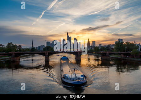 Frankfurt city view from river Main at sunset, with sailing cargo ship
