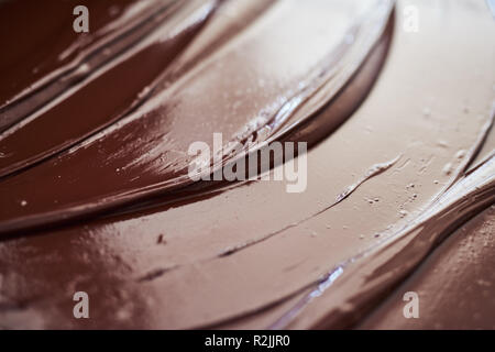 Glistening melted chocolate spread out on a table Stock Photo