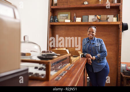 Smiling entrepreneur standing by a counter in her chocolate shop Stock Photo