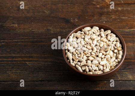 salted peanuts in a clay plate on a wooden background. place for text Stock Photo