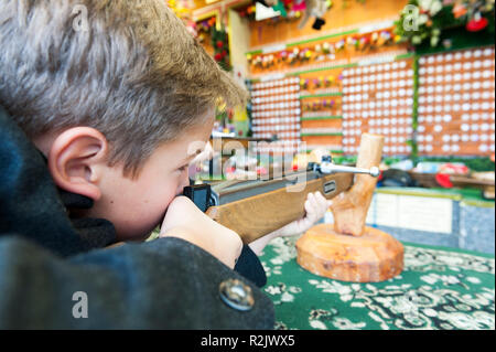 ten year old boy in traditional costume aiming with a rifle at a target, Munich, Oktoberfest Stock Photo