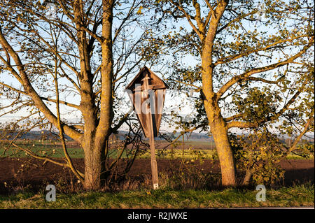 tilted wayside cross between two trees, Upper Bavaria, Bavaria, Germany, Europe Stock Photo