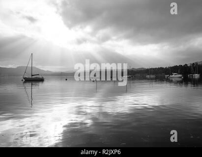 Black and White Image of Yachts and Boats Moored near Ambleside at Waterhead on Lake Windermere with Rays of Sunshine Cumbria England United Kingdom Stock Photo