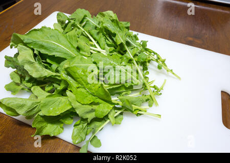 Arugula or rocket (Eruca sativa; syns. Eruca vesicaria) leaf vegetable on white cutting board, Asuncion, Paraguay Stock Photo