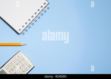 Notepad, calculator and pencil on blue background Stock Photo