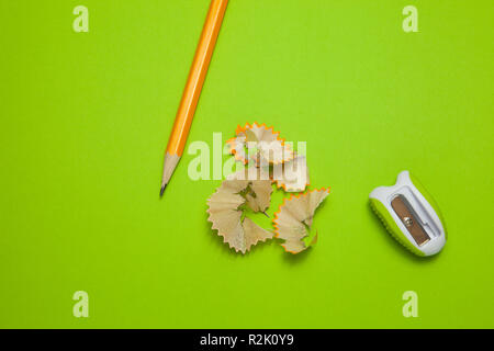 Sharpened pencil and sharpener on green background, top view Stock Photo