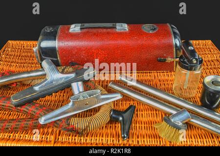 Vintage vacuum cleaner. Retro vacuum cleaner vintage with accessories on wicker box. Black background. Stock Photo