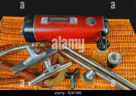 Vintage vacuum cleaner. Retro vacuum cleaner vintage with accessories on wicker box. Black background. Stock Photo