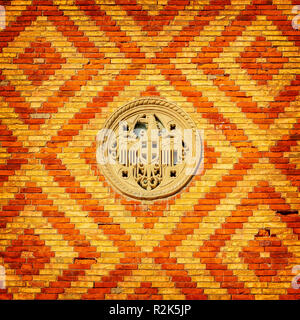 An ornate patterned brick wall with a stone eagle decoration. Stock Photo