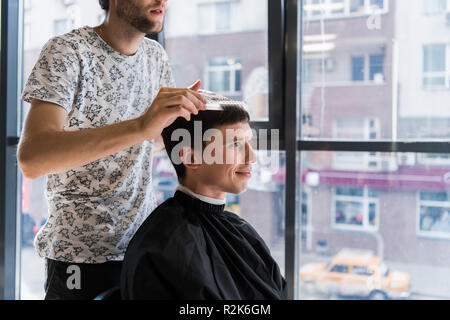 Man getting hair cut by scissor in barbershop. Barber use scissor and ...