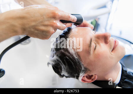 Hairstylist Hairdresser Washing Customer Hair - Young Man Relaxing In Hairdressing Beauty Salon. Stock Photo