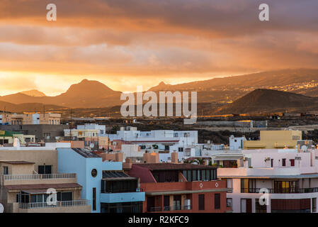 Building of the coastal town of El Medano at sunset in front of the volcanic landscape of Tenerife. Stock Photo