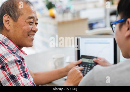 Son helping senior father paying bills at laptop Stock Photo