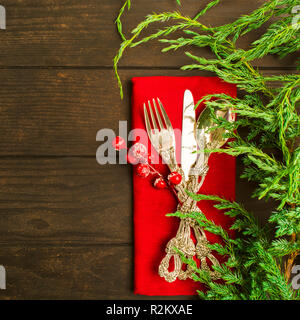 Christmas silverware on red tissue with green fir tree on wooden table Stock Photo