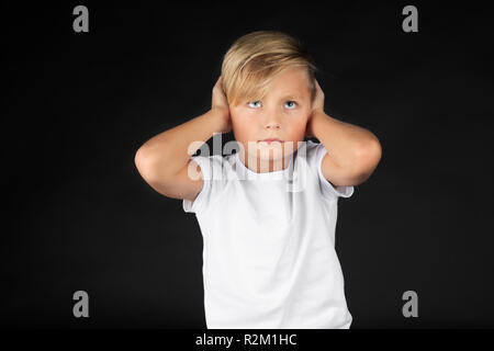 Little blond boy covers his ears Stock Photo