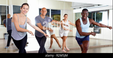 Cheerful  glad smiling people practicing vigorous lindy hop movements in dance class Stock Photo