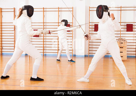 Two women fencers practicing techniques in duel at the fencing sparring Stock Photo