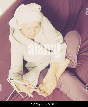 Senior woman starting feet pedicuring with special devices at home Stock Photo