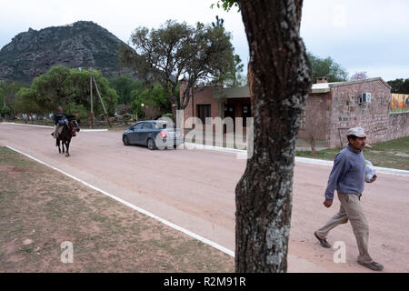 A horse rider and a pedestrian travel through the small village of Cerro Colorado in Córdoba, Argentina Stock Photo