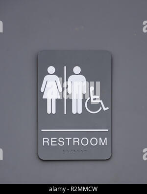 A gray and white unisex restroom sign on a bathroom door with handicapped or disabilities access. Stock Photo