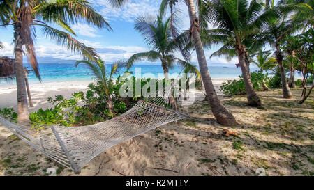 Hammock on the beach, surrounded by palm trees, Fiji Stock Photo