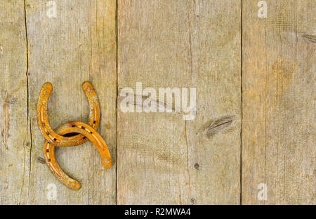 Two rusty horseshoes hang together on a wooden wall Stock Photo