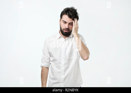 Bearded man with messy hair and beard, rubbing head and being tired or having hangover Stock Photo