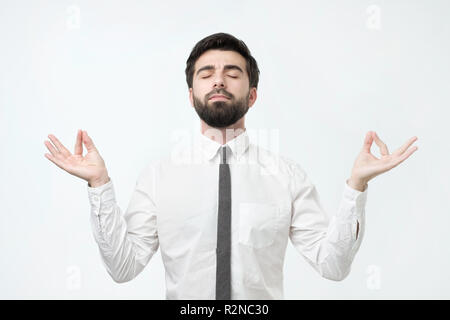 Concentrated bearded hispanic man with meditates, tries to relax after hard working day Stock Photo