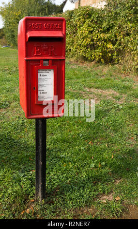 A pole mounted Royal mail collection box in Sawbridgeworth, Hertfordshire from the reign of Queen Elizabeth II, ER, on the green Stock Photo