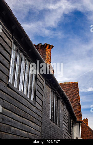 An old property with a mixture of bricks and wood cladding under a blue sky. Ornate chimneys point upwards in Sawbridgeworth, Hertfordshire Stock Photo