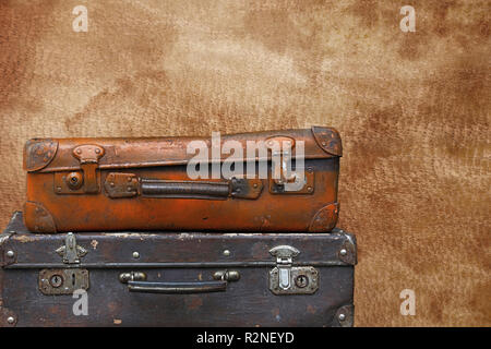 Close up stack of two old vintage antique grunge travel luggage brown leather suitcase trunks isolated over background of brown leather, low angle sid Stock Photo
