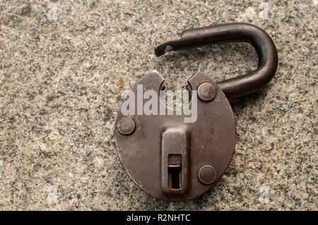 Old weathered grunge retro open padlock closeup on solid stone surface background Stock Photo