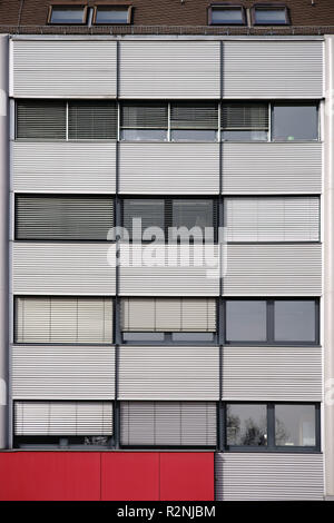 Modern facade of an office building with rows of windows and metal blinds,