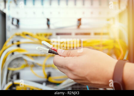 IT specialist connects fiber optic cables to the network equipment. IT infrastructure and data line Stock Photo