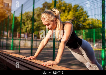 Young woman athlete doing push-ups on sportsground in summer. Healthy lifestyle. Motivation Stock Photo