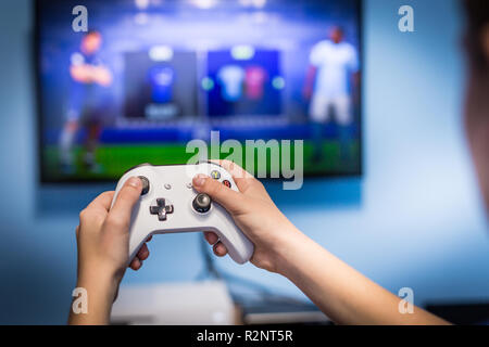 Young hipster man playing video game football soccer on console. gamer guy  with gamepad controller holding Wireless joystick sitting on pouf at night  Stock Photo - Alamy