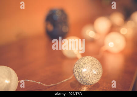 Christmas and New Year cotton ball light garland in a vintage wood tray, on planked wood background, rustic minimalist style, close up Stock Photo